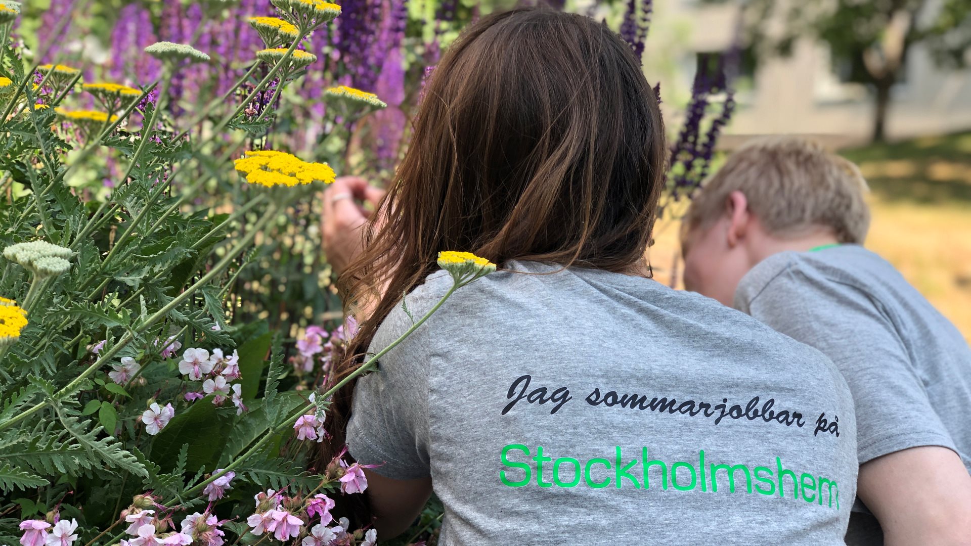Två ungdomar pysslar om en blomsterrabatt