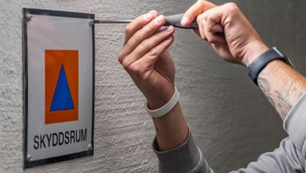 Manshänder skruvar upp skyddsrumsskylt