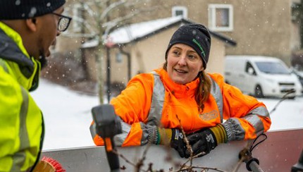 Kvinna i mössa och varselkläder i snöfall 