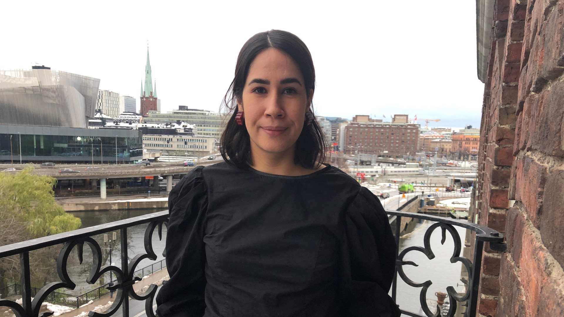 Kvinna på balkong med Stockholms city i bakgrunden
