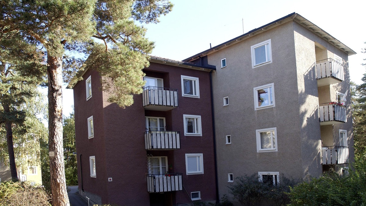 Flerfamiljshus med putsad fasad i vinrött och beige.