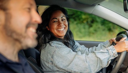 Glad kvinna kör bil och tittar på leende man