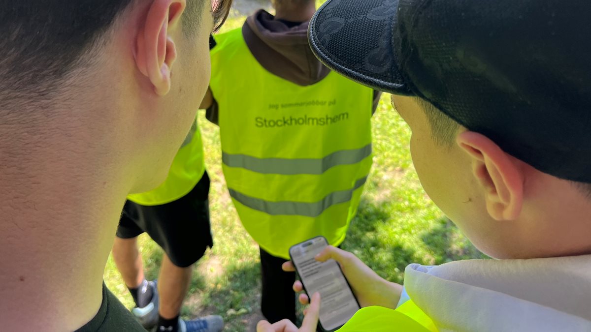 Ungdomar i varselvästar tittar på sina telefoner