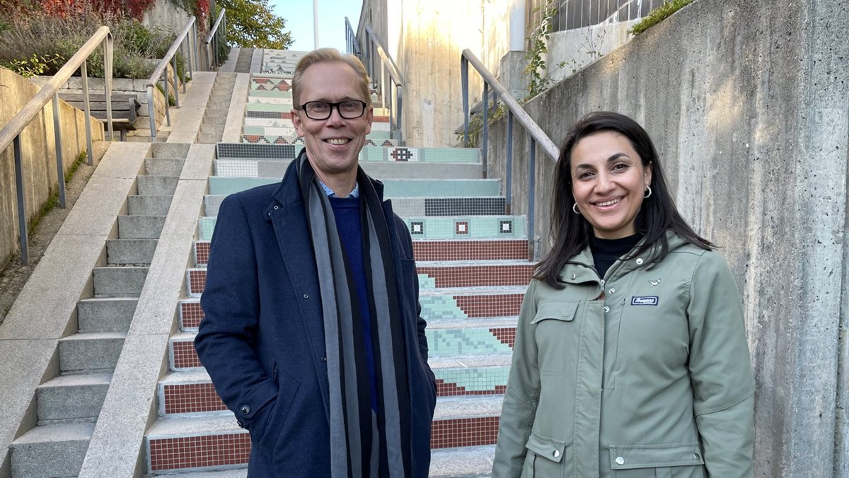Leende man och kvinna framför en trappa, smyckad med mosaik