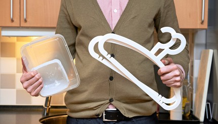 man håller plastförpackningar och plastgalgar