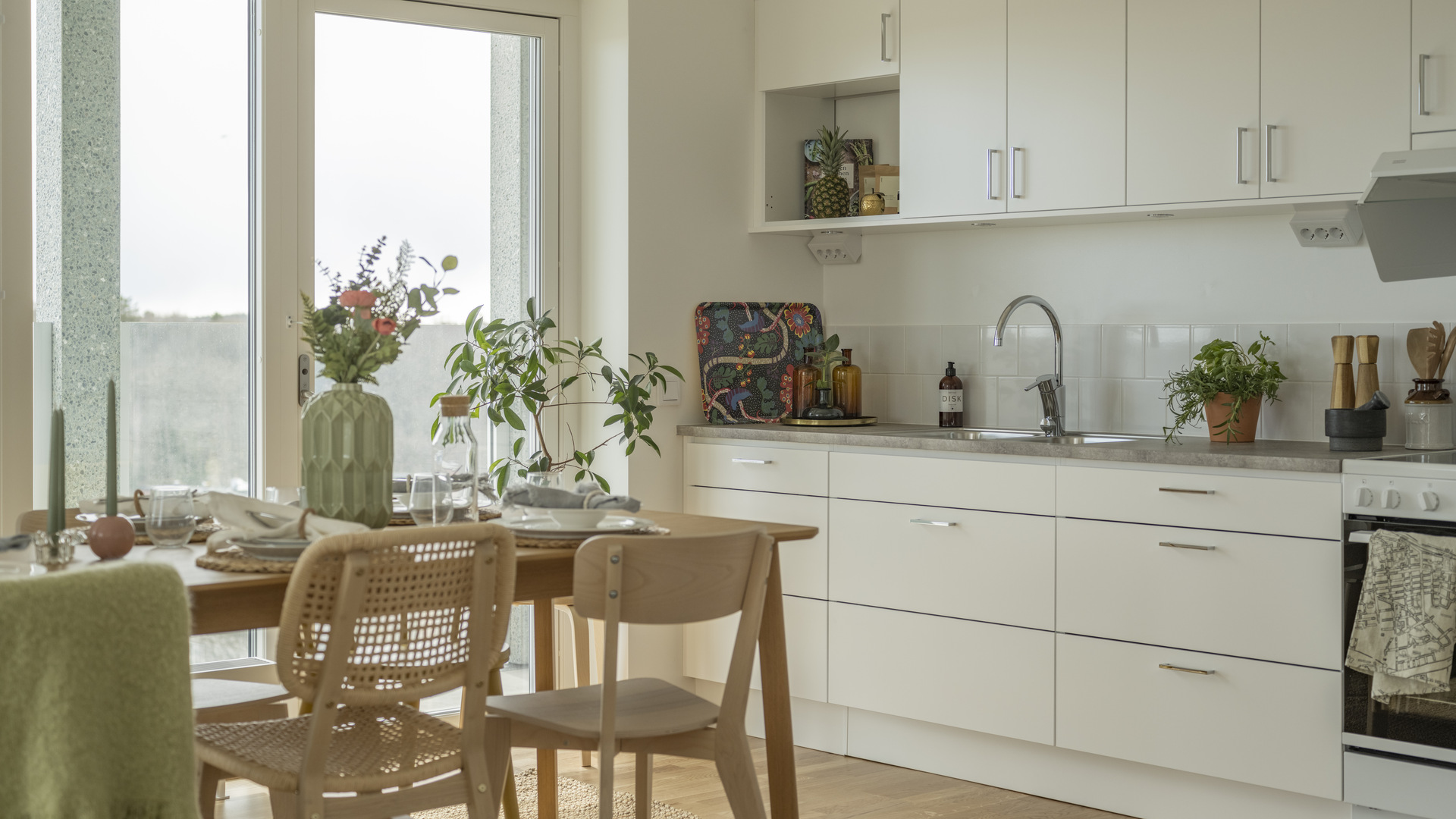 Kök med ljusa skåpsluckor, dukat bord