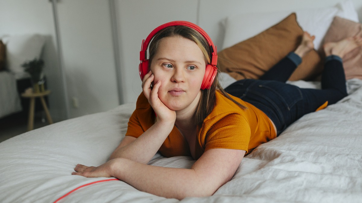 Flicka med hörlurar på säng
