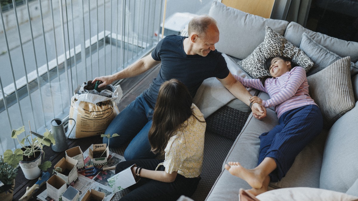 Pappa och två flickor planterar på balkong