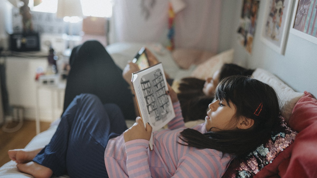 Två flickor läser på soffa