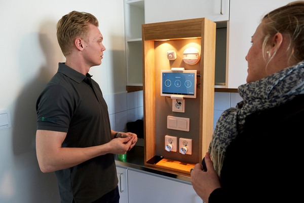 Man och kvinna tittar på system för belysning och inomhustemperatur. 