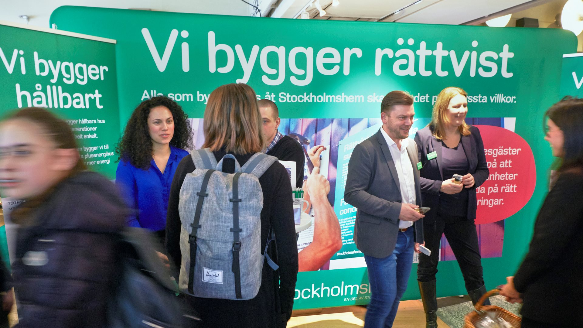 Flera män och kvinnor som står i en monter på en mässa.