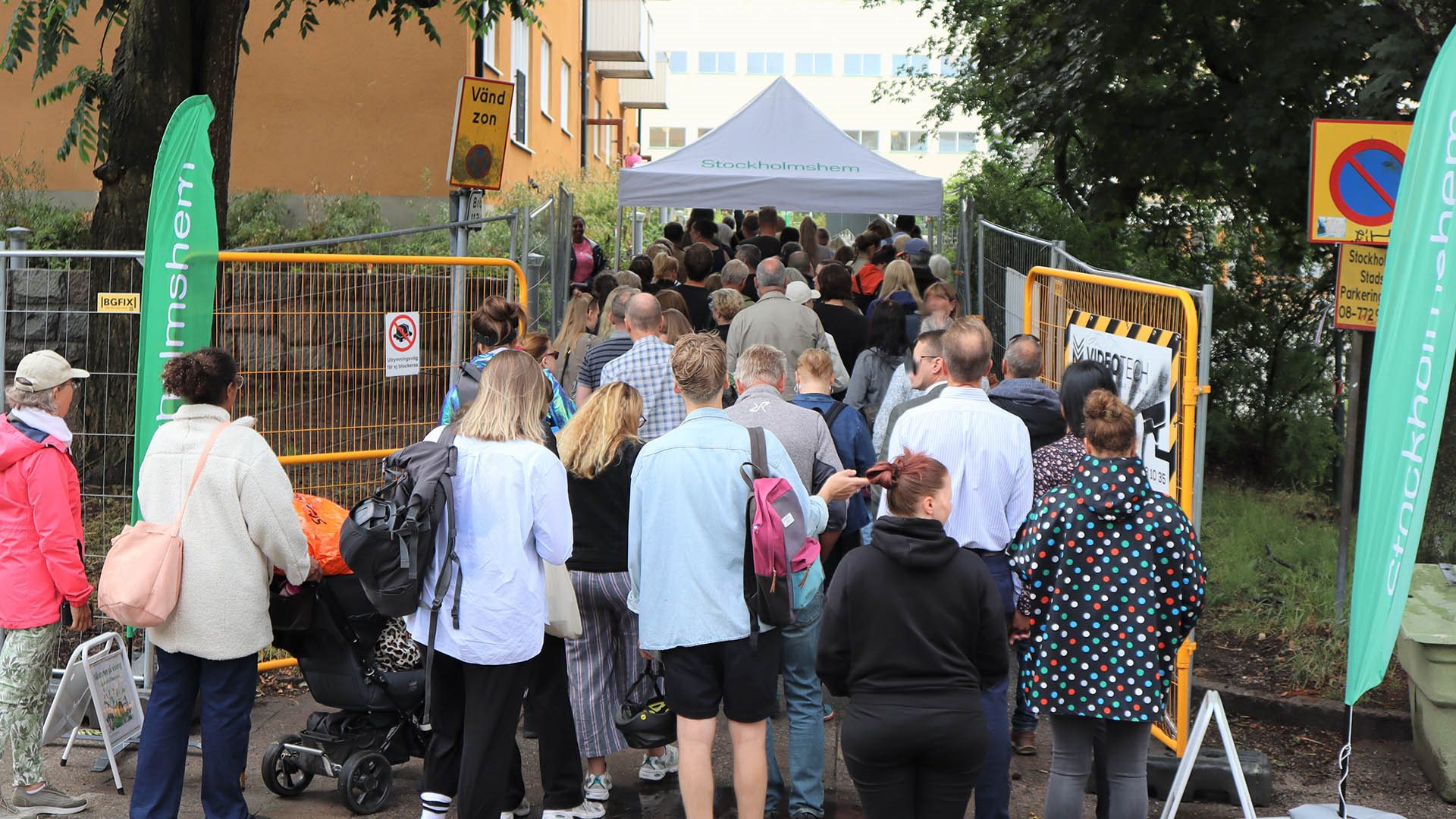 Folksamling köar utanför hus