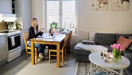 Ung kvinna vid köksbord i liten lägenhet