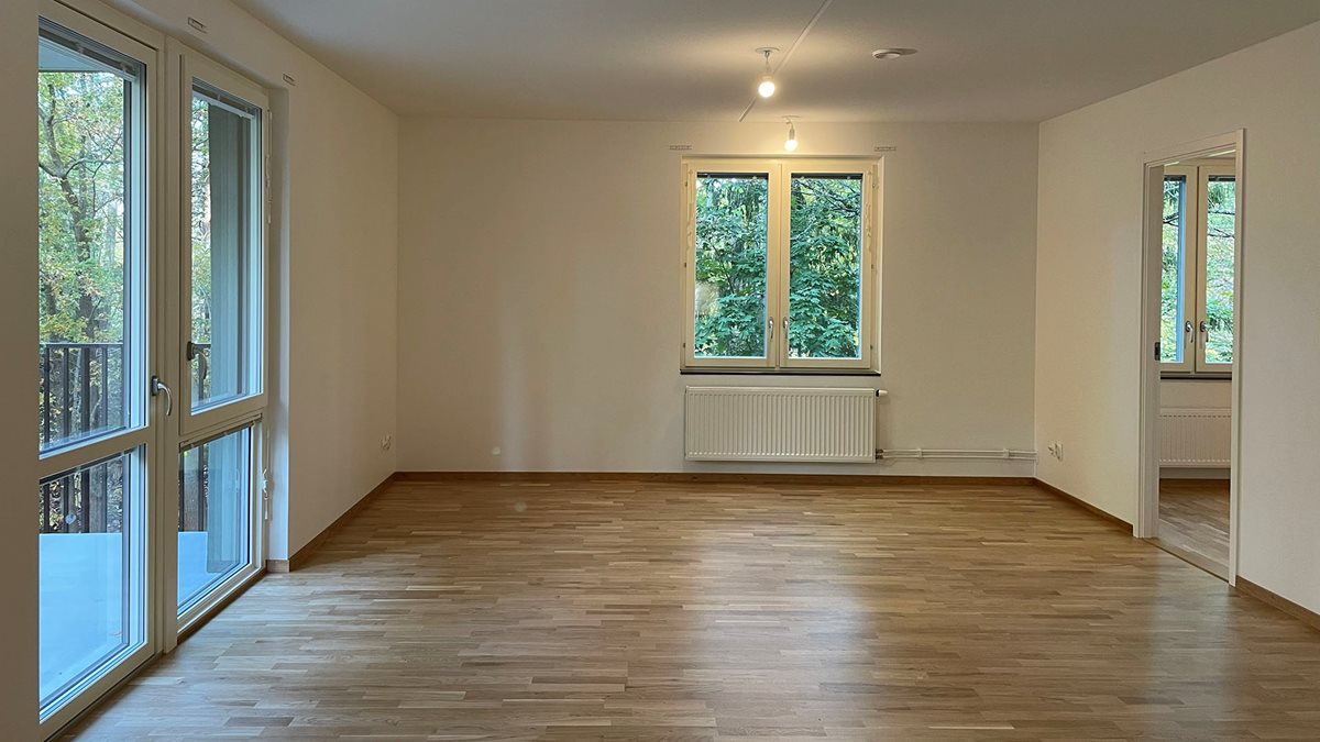 Tomt vardagsrum med parkett och vita väggar